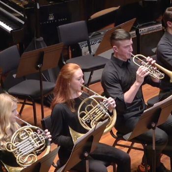 Hannah plays the French Horn next to other ensemble players